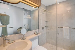 A modern bathroom with a sink, mirror, and glass-enclosed shower.