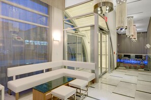 Un interior moderno con un banco blanco, una mesa de vidrio y una zona de bar con iluminación azul.