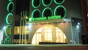 Un edificio con una serie de ventanas circulares iluminadas y el nombre 'Wyndham Garden' exhibido de forma destacada.