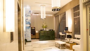 Un moderno vestíbulo de hotel con una recepción, zona de estar y un amplio ventanal.