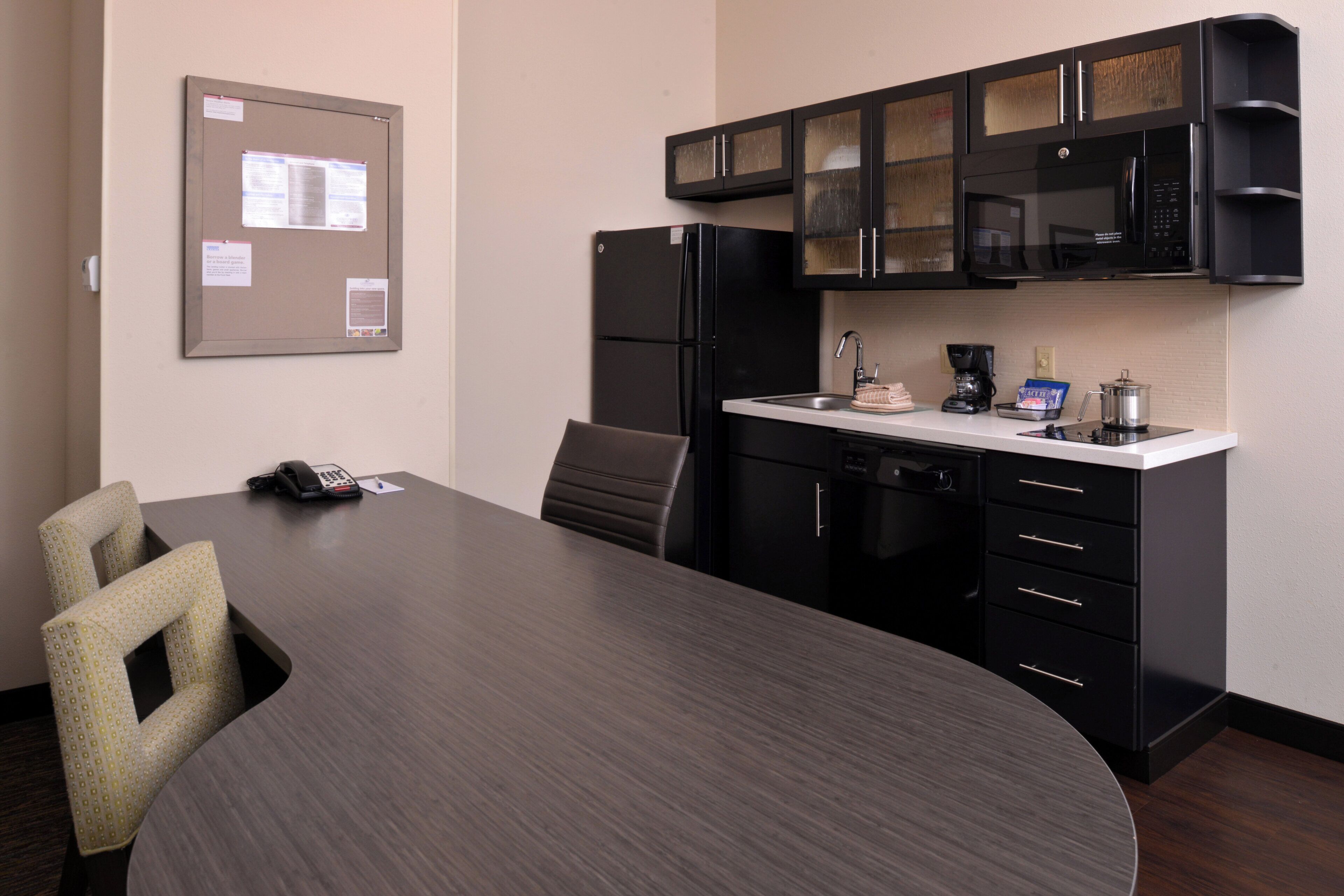A conference room with a long table, chairs, a telephone, and a bulletin board.
