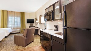A hotel room with a bed, a sofa, a desk, a refrigerator, a microwave, a sink, and a television. - Candlewood Suites MORGANTOWN-UNIV WEST VIRGINIA by IHG (Morgantown)