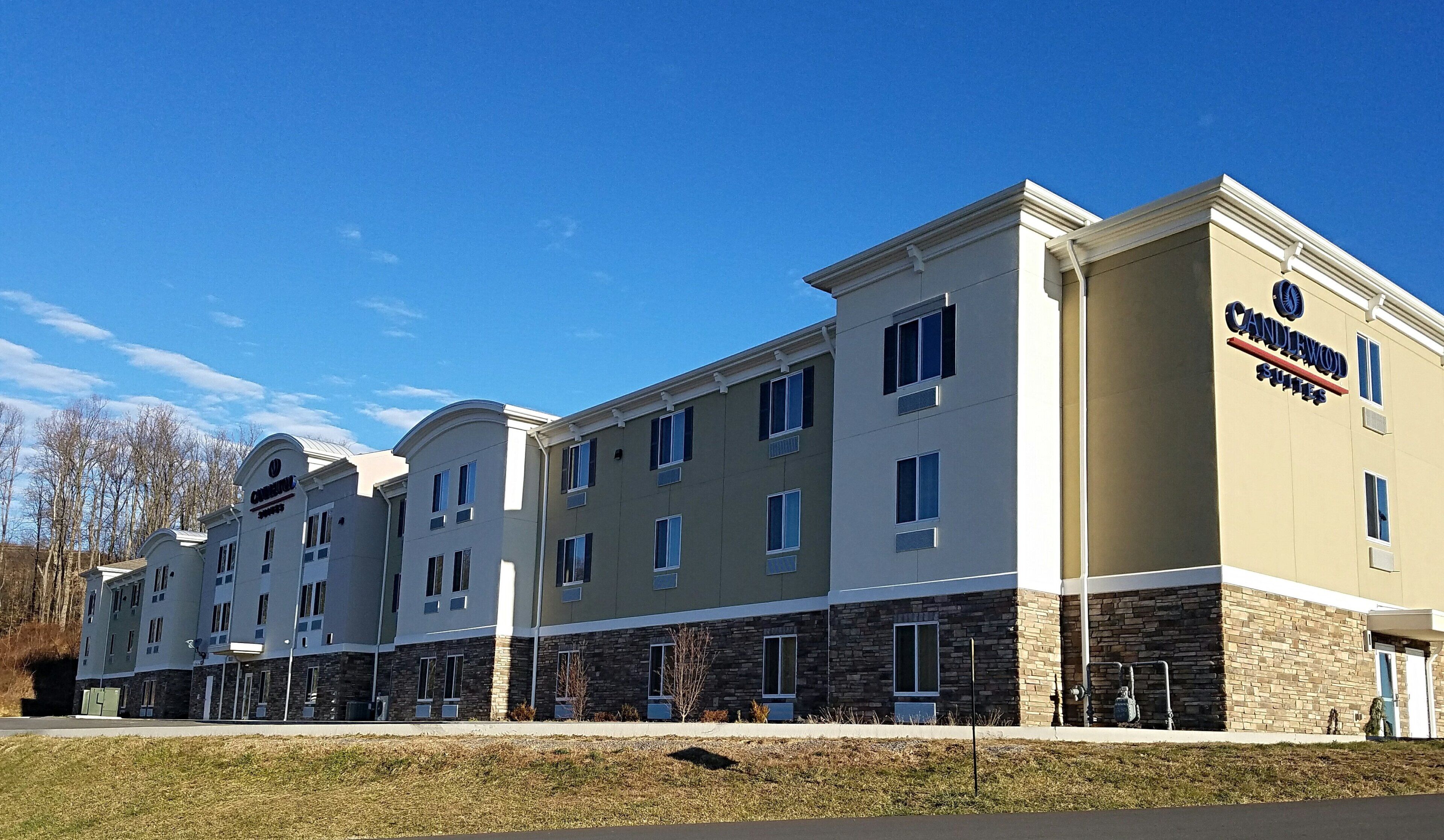 A hotel with a modern design, featuring a mix of stone and stucco exteriors, multiple windows, and a prominent signage for 'Candlewood Suites'.