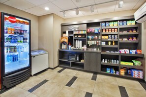 A self-service kiosk with a Coca-Cola refrigerator, a coffee machine, and a variety of snacks and condiments. - Candlewood Suites MORGANTOWN-UNIV WEST VIRGINIA by IHG (Morgantown)