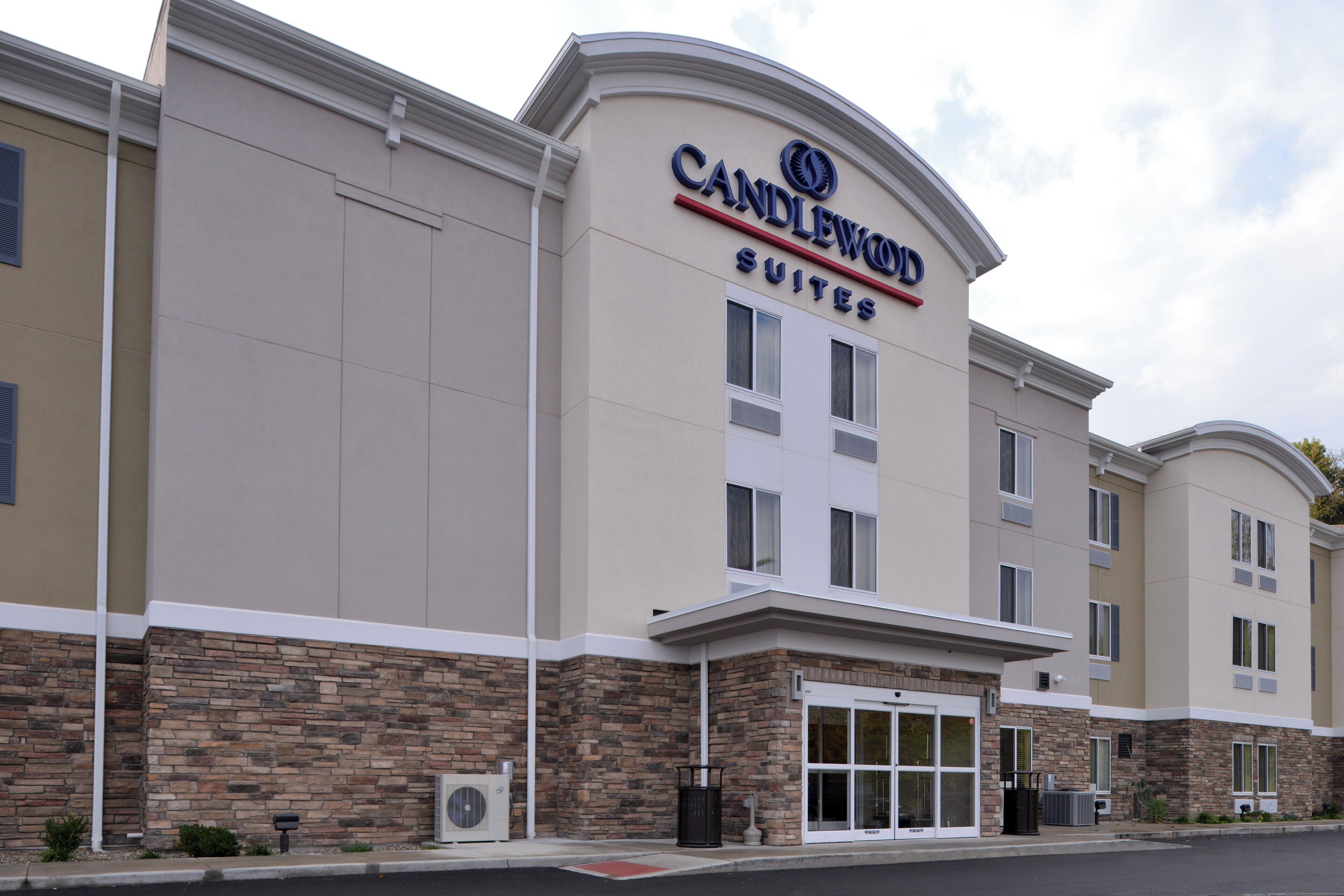 Um hotel com fachada moderna, placa chamativa com 'CANDLEWOOD SUITES' e exterior limpo e bem cuidado.