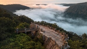 A stone bridge with railings leading to a cliff edge overlooking a valley with dense forests and a layer of clouds below. - Candlewood Suites MORGANTOWN-UNIV WEST VIRGINIA by IHG (Morgantown)