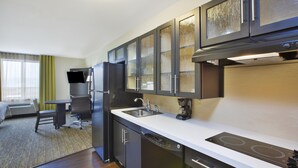 A compact hotel kitchen with a refrigerator, stove, and dishwasher. - Candlewood Suites MORGANTOWN-UNIV WEST VIRGINIA by IHG (Morgantown)
