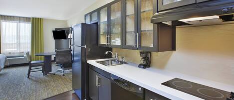 Cocina de hotel compacta con estufa integrada, lavaplatos y refrigerador.