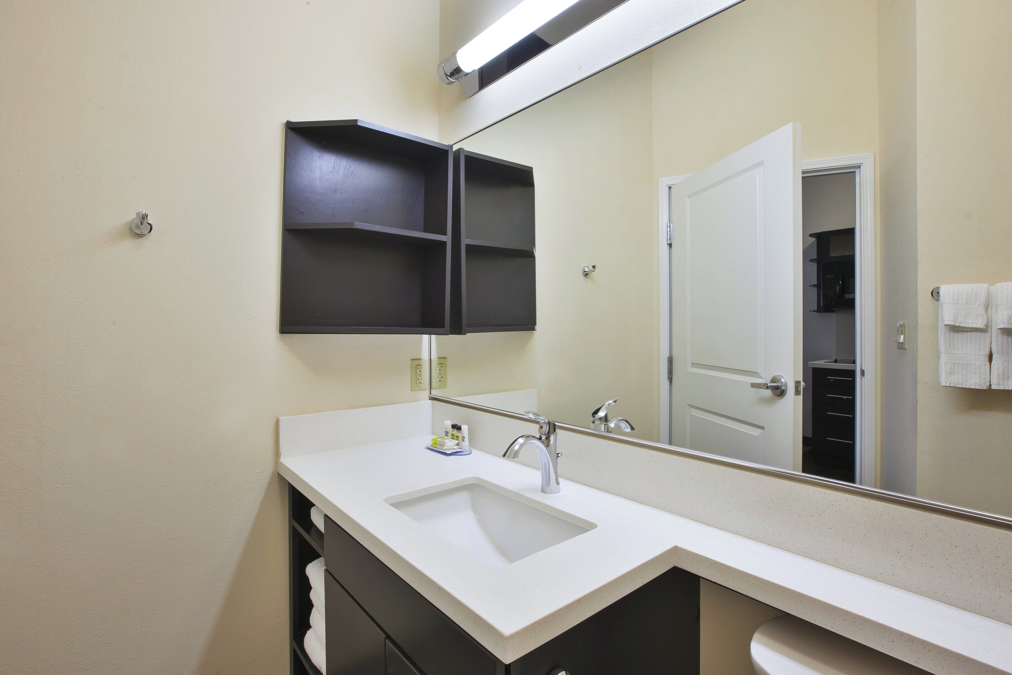 A bathroom with a white sink, a mirror, and a black medicine cabinet.
