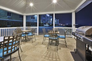 An outdoor patio with a grill, chairs, and a view of the city at night. - Candlewood Suites MORGANTOWN-UNIV WEST VIRGINIA by IHG (Morgantown)