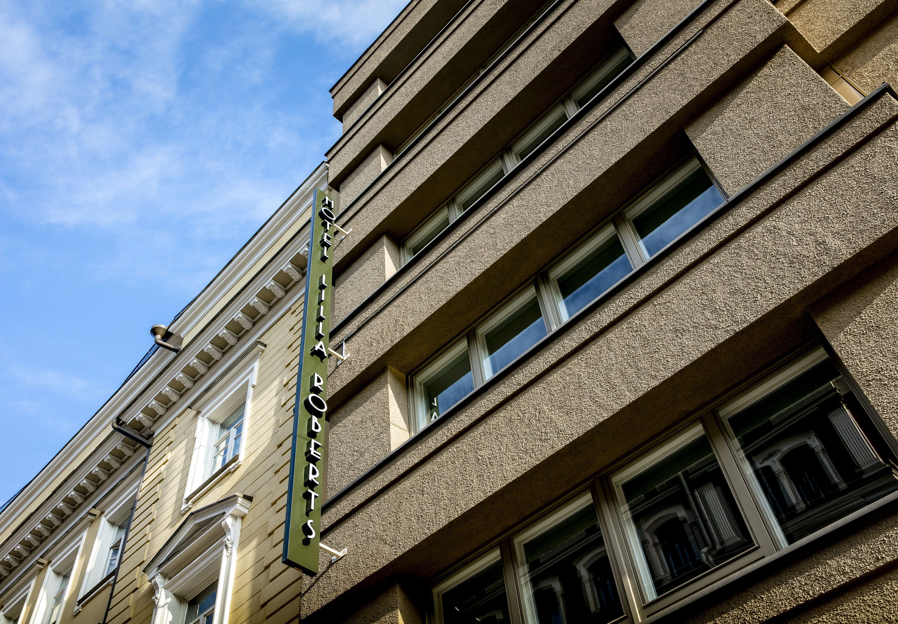 A hotel facade with a classic architectural design, featuring multiple windows and a prominent sign.
