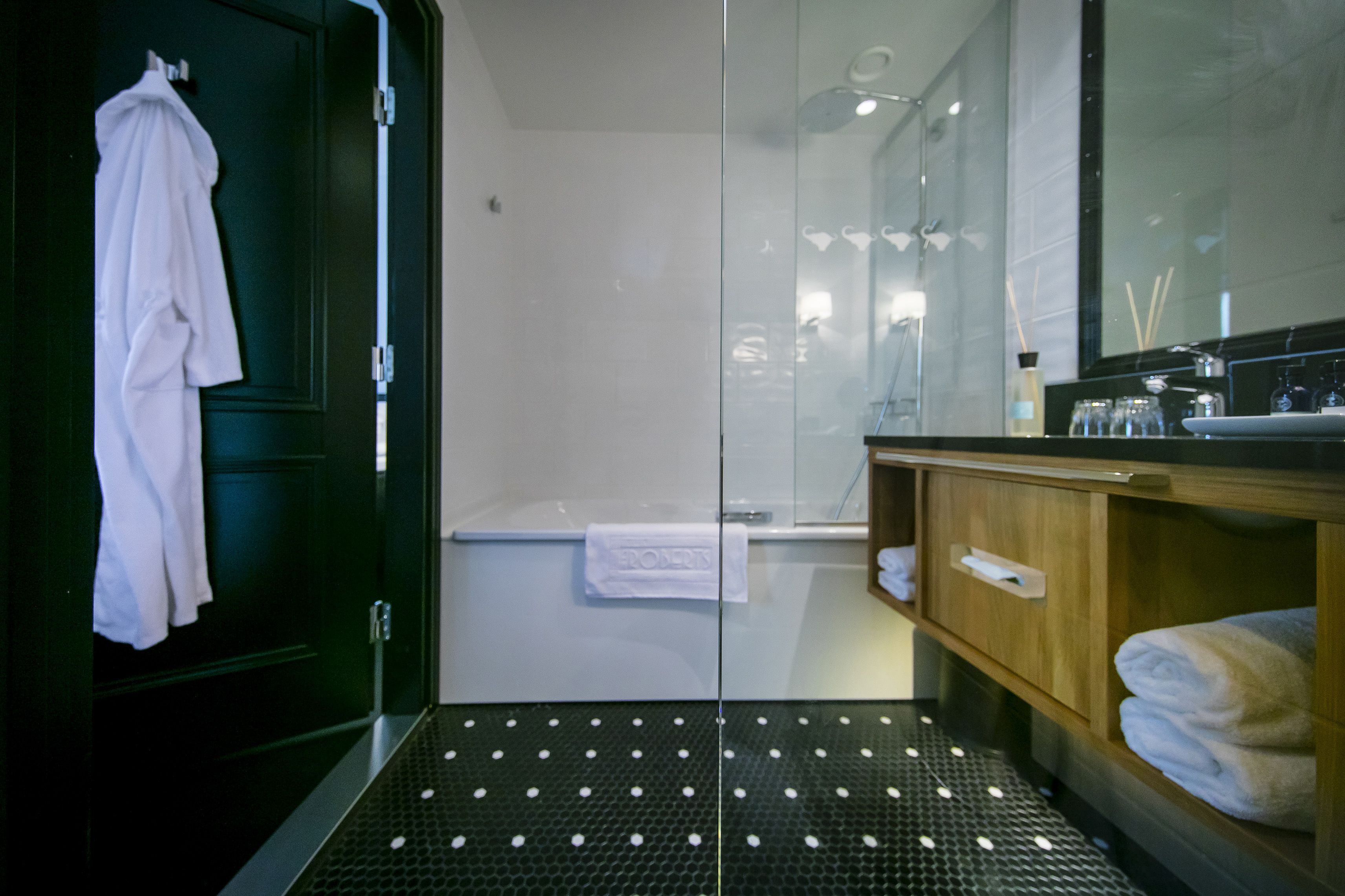 A modern bathroom with a glass shower enclosure, a wooden vanity with a sink, and a towel rack.