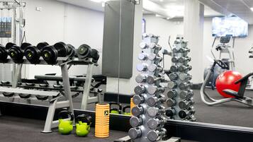 A gym with various exercise equipment, including dumbbells, kettlebells, and a red exercise ball.