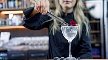 A bartender preparing a drink in a bar setting.