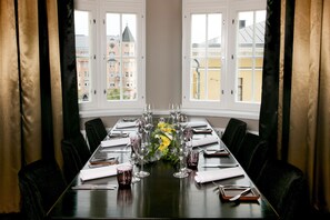 A conference table set for a meeting with chairs, a vase of yellow flowers, and wine glasses. - Hotel Lilla Roberts (Helsinki)