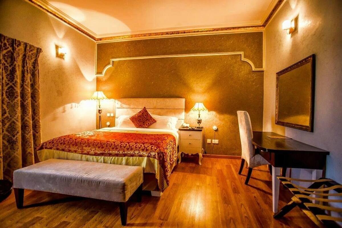 A bedroom with a bed, bedside tables, a desk, and a chair.