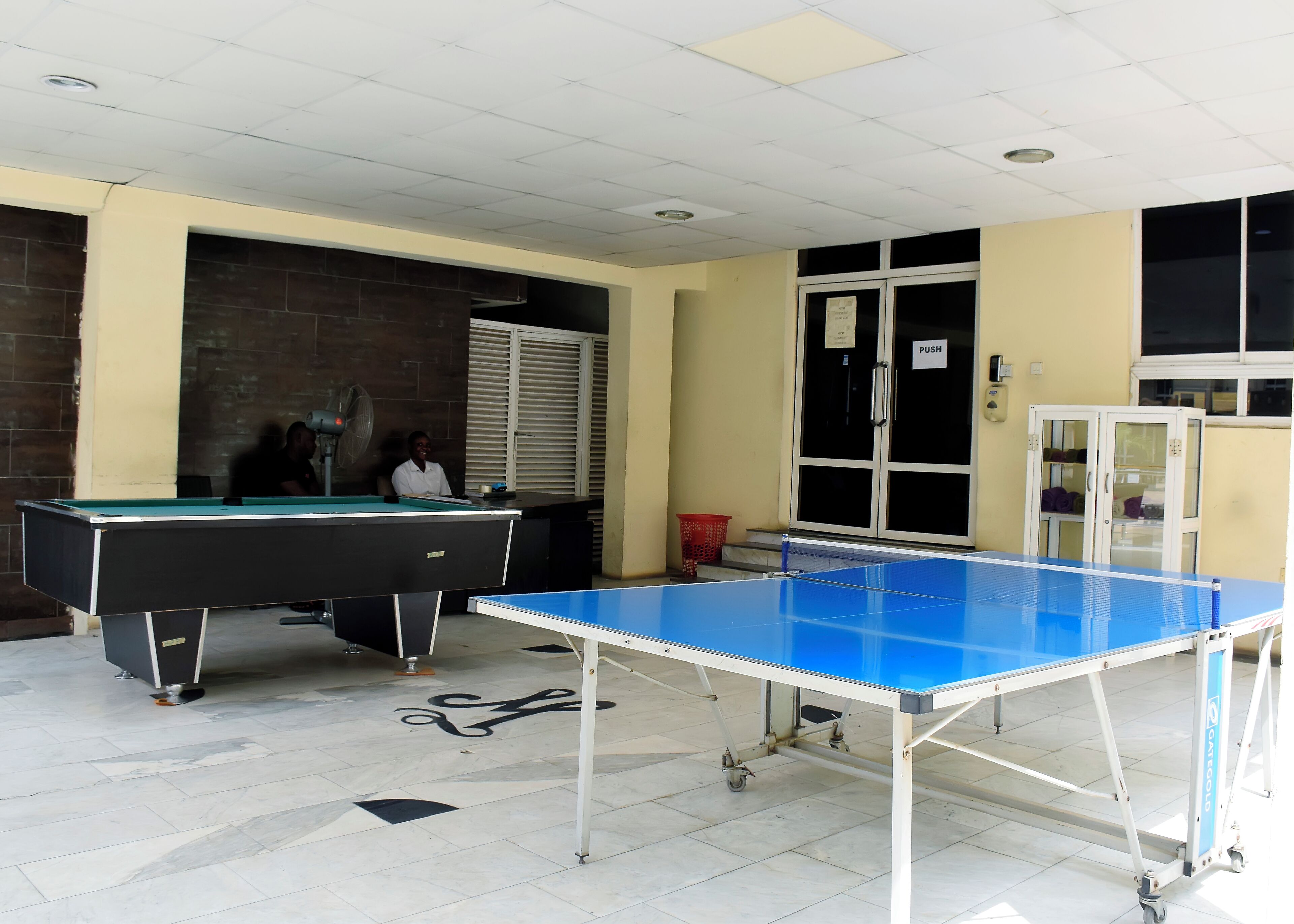 A room with a pool table, a ping pong table, and a cabinet with glass doors.