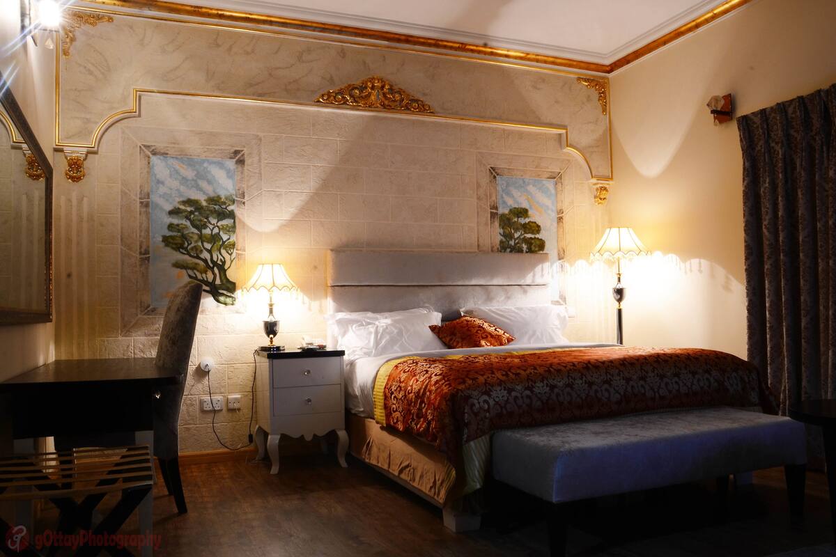 A hotel room with a bed, bedside lamps, a desk, and a chair.