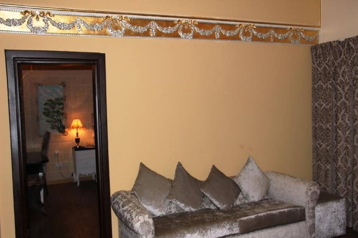 A living room with a sofa, a lamp, and a patterned curtain.
