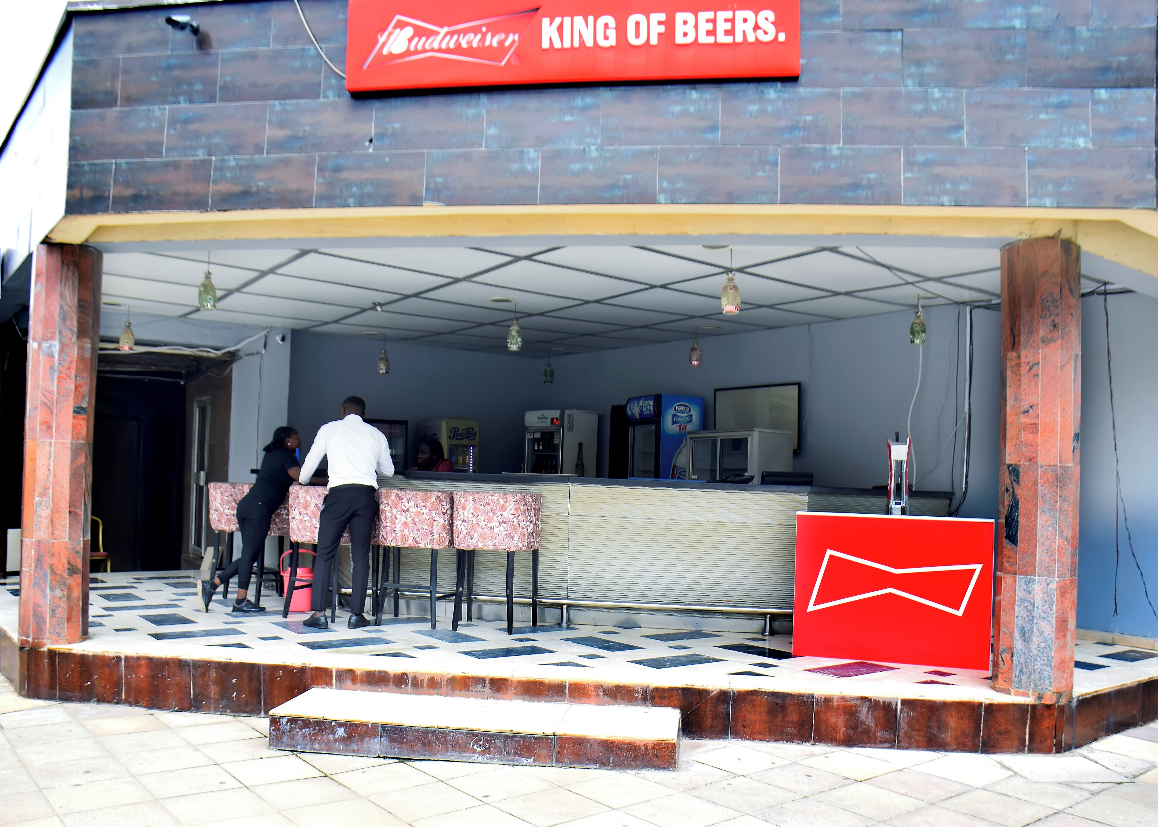 A Budweiser establishment with a tiled floor, a counter, and a sign stating "King of Beers."