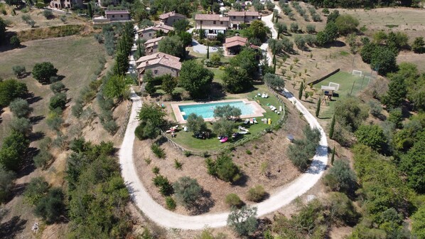 Vista aérea de um bairro residencial com piscina, trilha sinuosa, casas e vegetação.