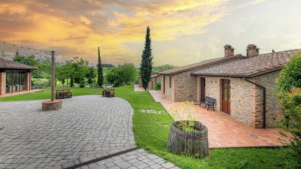 A courtyard with stone buildings, a paved walkway, and benches. - PanElios Borgo Vacanze (Citta della Pieve)