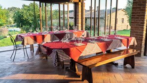 An outdoor dining area with checkered tablecloths and wooden benches. Tables are set with wine glasses, cutlery, and napkins. - PanElios Borgo Vacanze (Citta della Pieve)