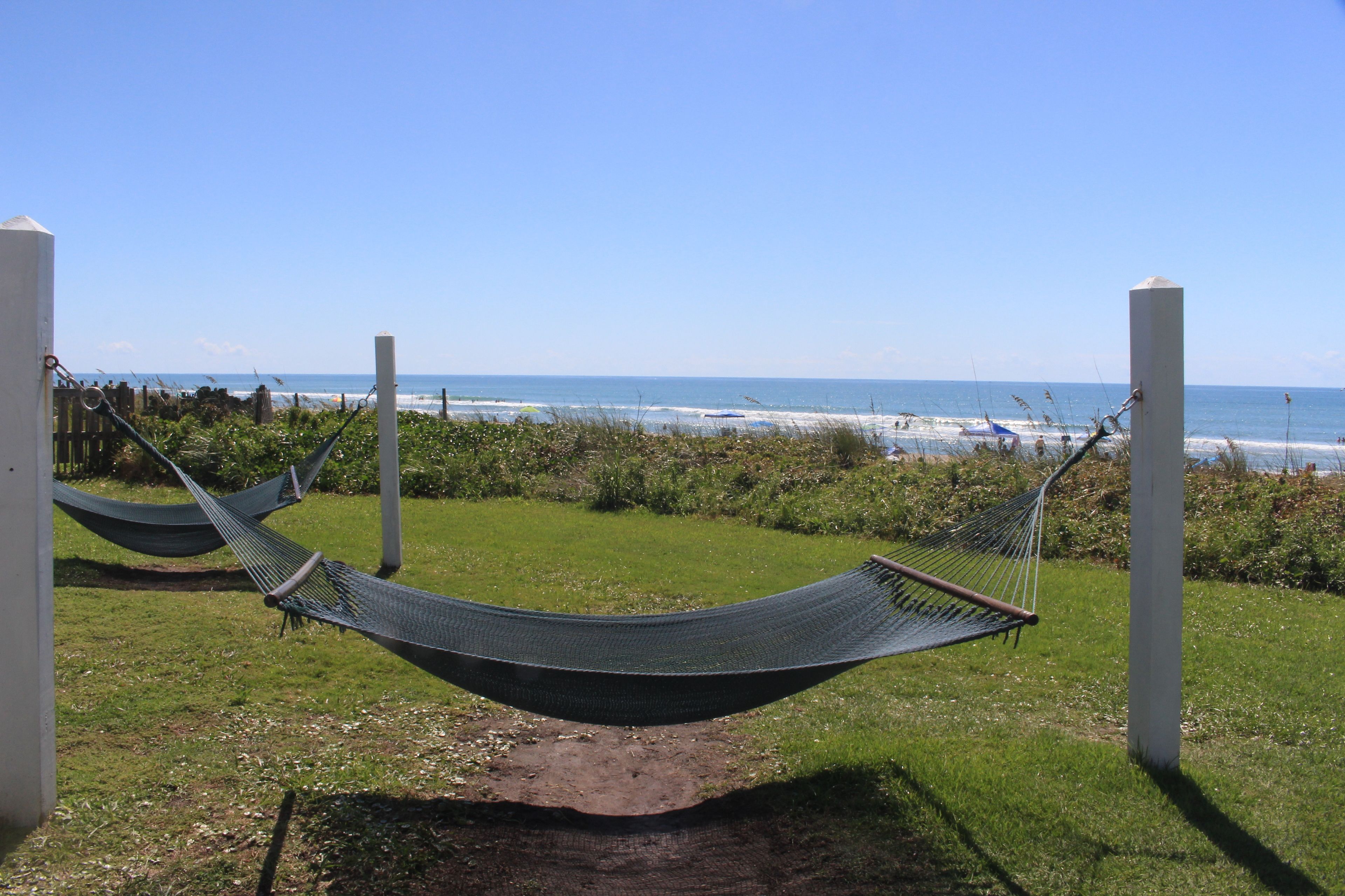 Een hangmat op een gazon met uitzicht op het strand en de oceaan.