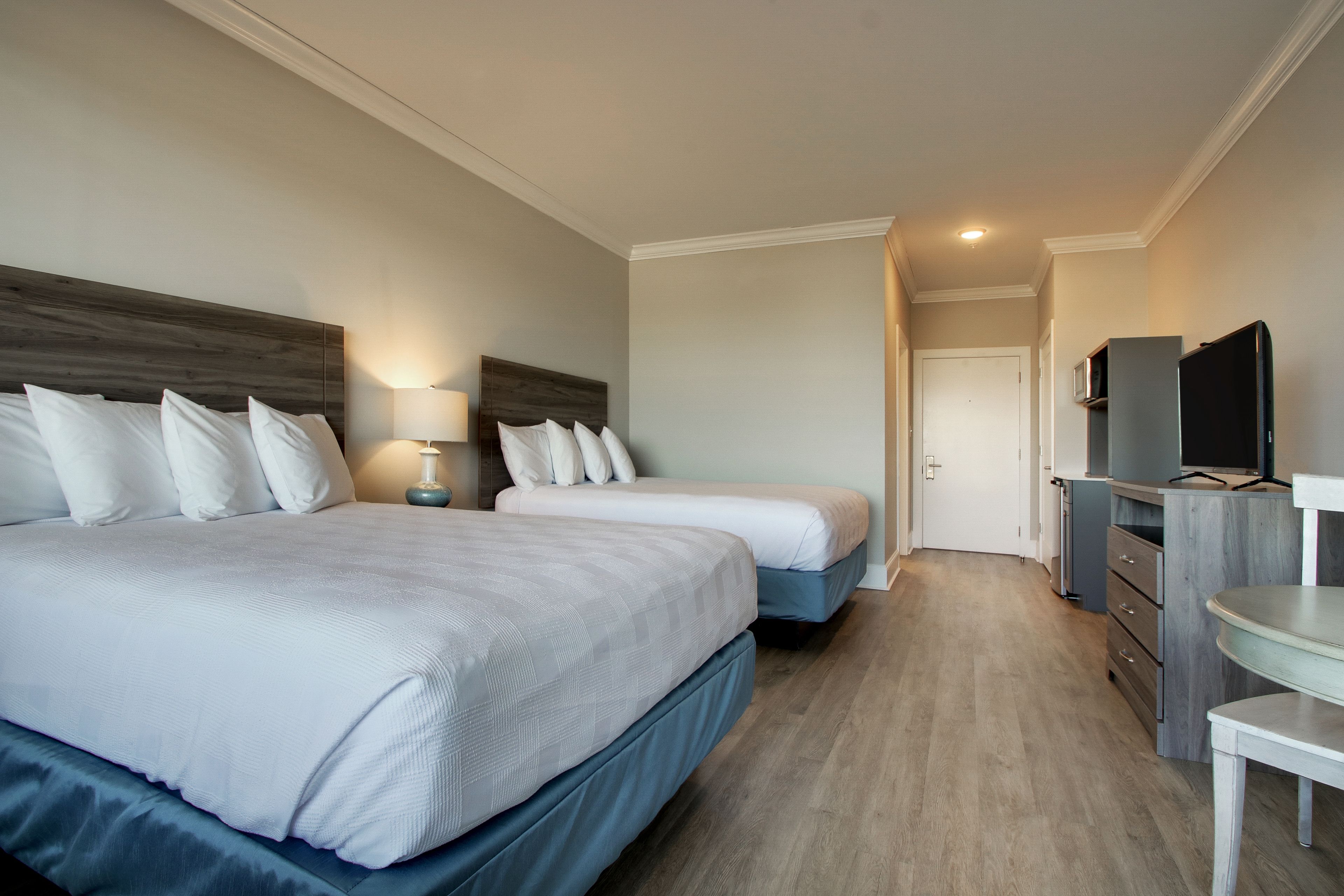 A hotel room with two beds, a TV, a desk, and a dresser.