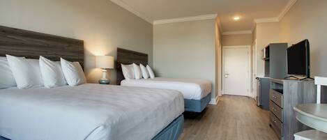 A hotel room with two beds, a TV, a desk, and a dresser.