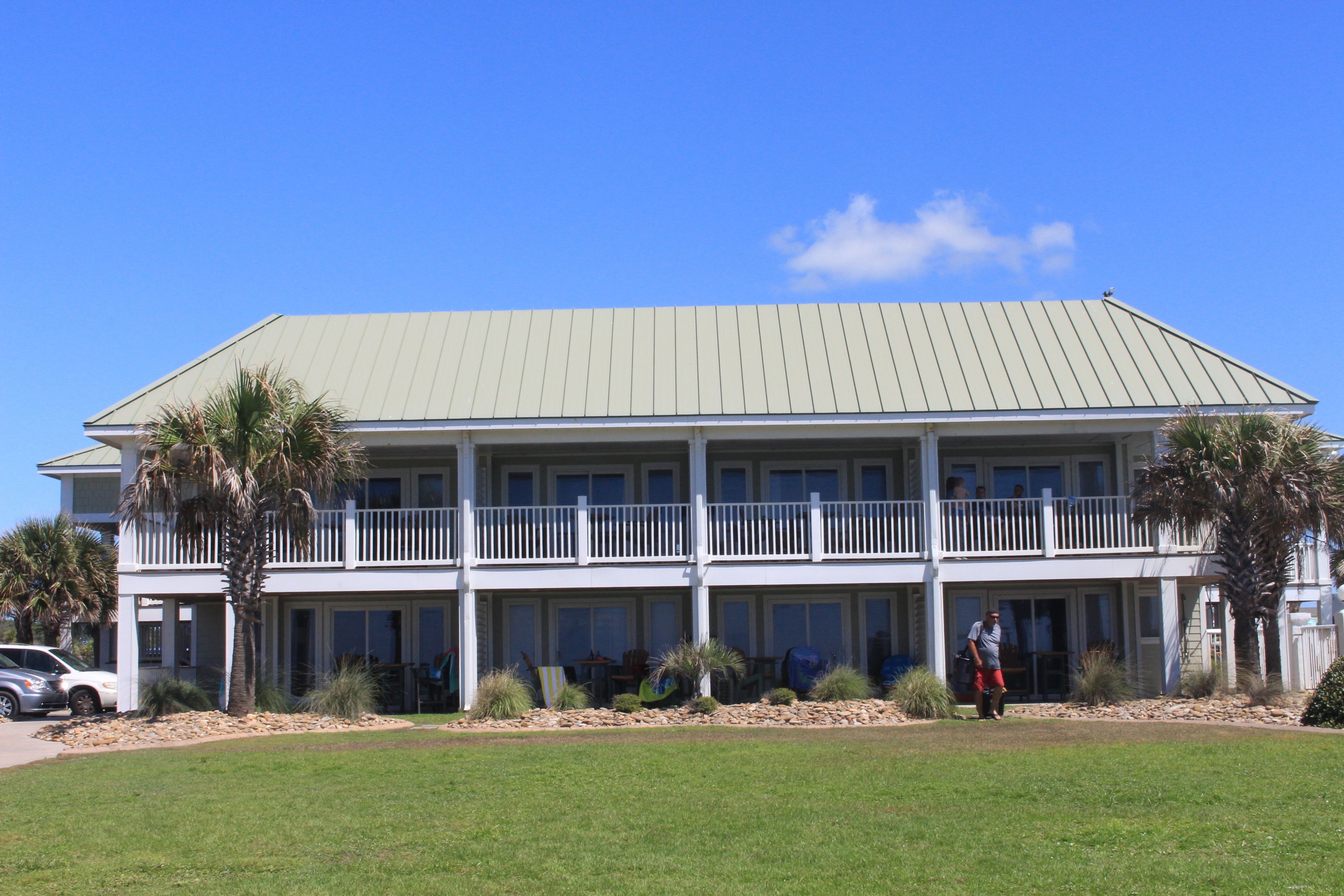 A two-story building with a flat roof and a balcony on the upper floor.