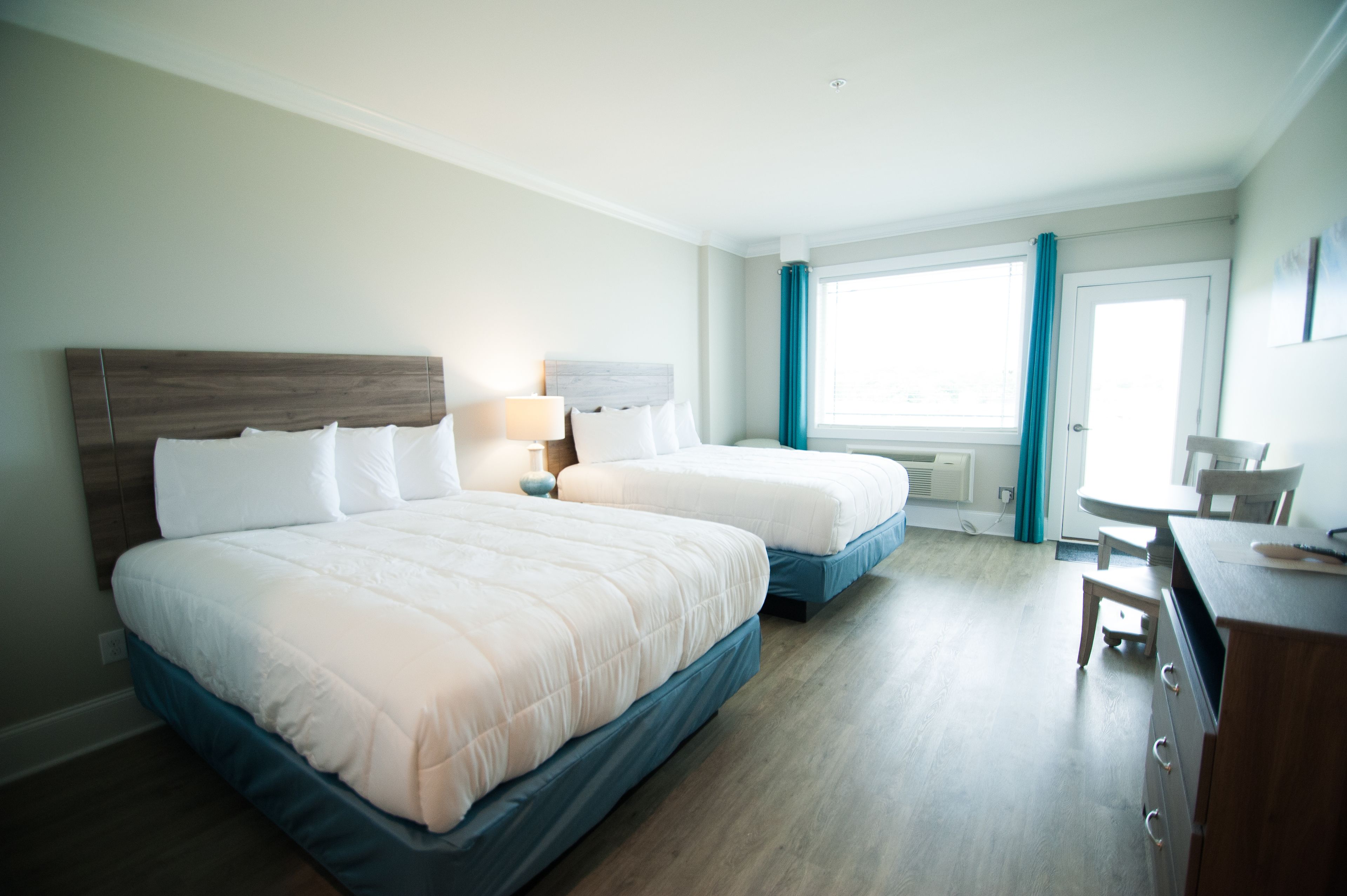 A hotel room with two beds, a desk, and a window with curtains.