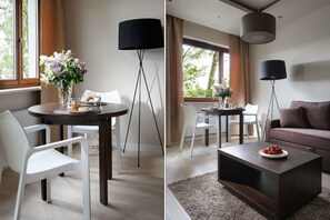 A modern living room with a dark coffee table, a sofa, and a dining area with a table and chairs. - Chopin Apartments Capital (Warsaw)