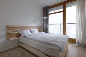Una camera da letto moderna con una testiera in legno, una coperta bianca e un comodino.