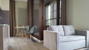 A modern living room with a grey sofa, a dining table with chairs, and a kitchen area with a sink and countertop. - Chopin Apartments City (Warsaw)