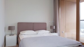 A neatly arranged bedroom with a bed, two bedside tables, and a large window. - Chopin Apartments City (Warsaw)