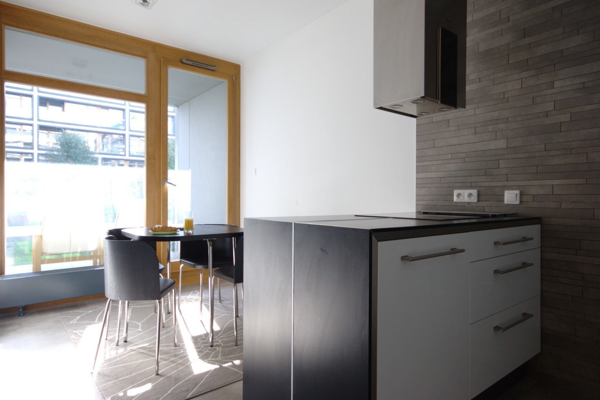 A modern kitchen with a built-in stove, white cabinets, and a dining area with a table and chairs.