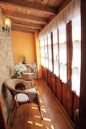 A cozy room with wicker furniture, a stone wall, and a wooden ceiling. - Muiño das Cañotas (Carino)