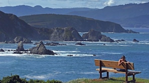 A bench overlooking a coastal area with rocky outcrops and a view of the sea. - Muiño das Cañotas (Carino)