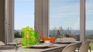 Een eettafel gedekt met borden, een glas, een groene karaf en een kom.