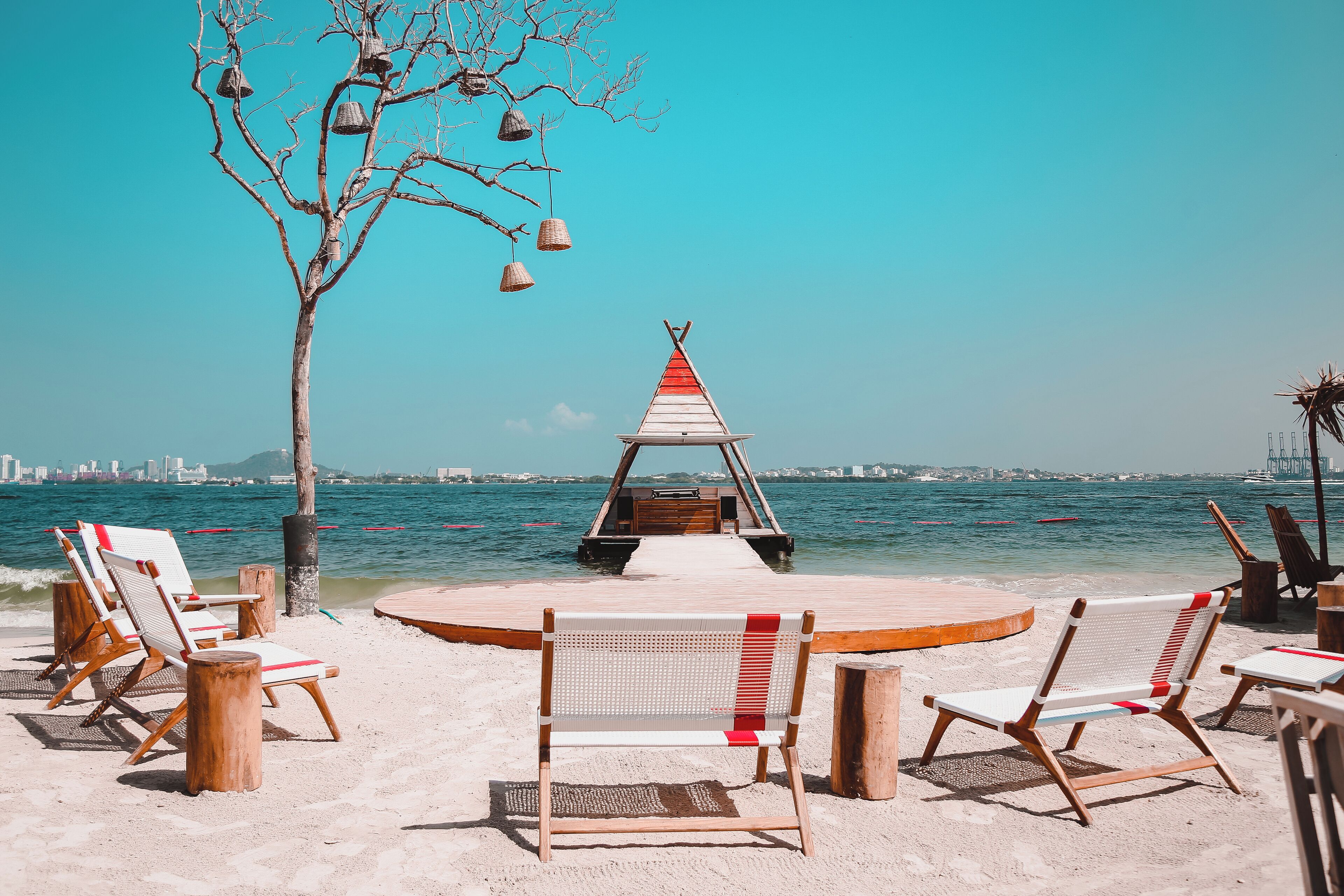A beachside setting with wooden chairs and a wooden structure with a red and white striped roof.