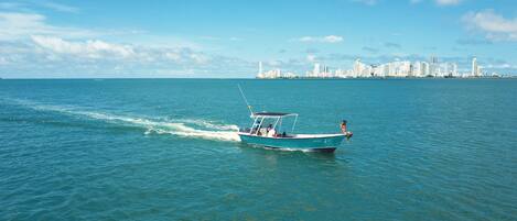 Un barco en un mar tranquilo con el perfil urbano al fondo.