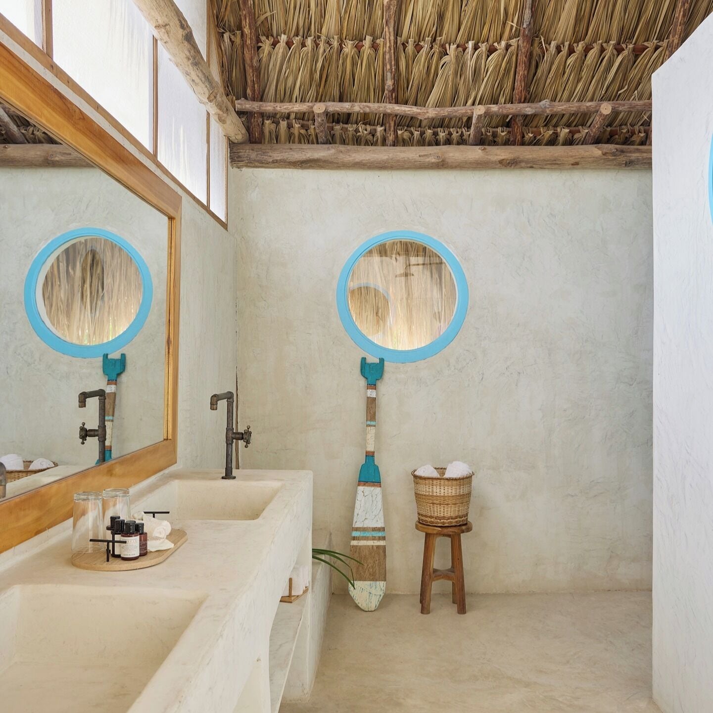 Une salle de bain avec un grand miroir, un lavabo et un petit tabouret.