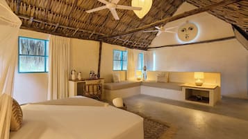 A bedroom with a bed, a desk, a sofa, and a ceiling fan.
