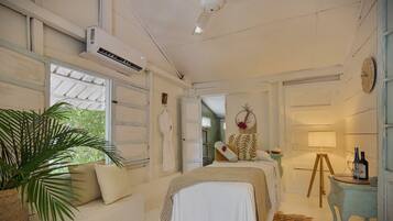 Un dormitorio con una cama, una mesita de noche, una lámpara y una planta grande.
