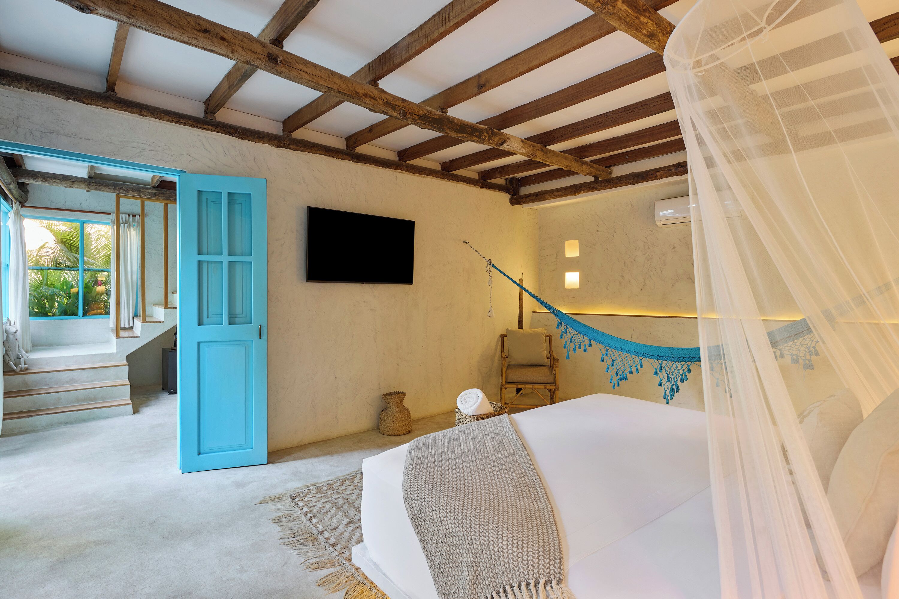 A bedroom with a bed, a TV, a chair, and a hammock.