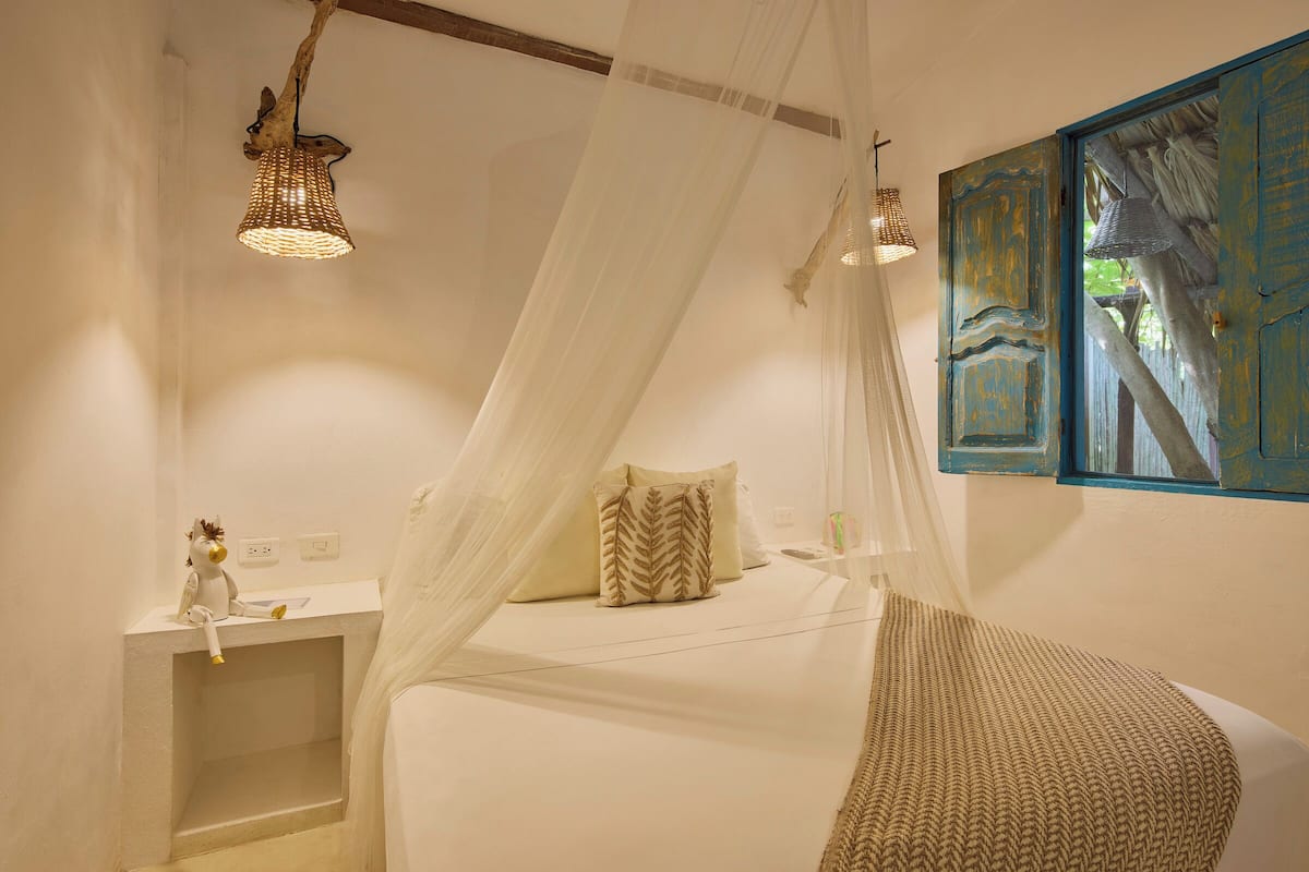 Une chambre à coucher avec un lit à baldaquin, une table de chevet et des œuvres d’art murales.