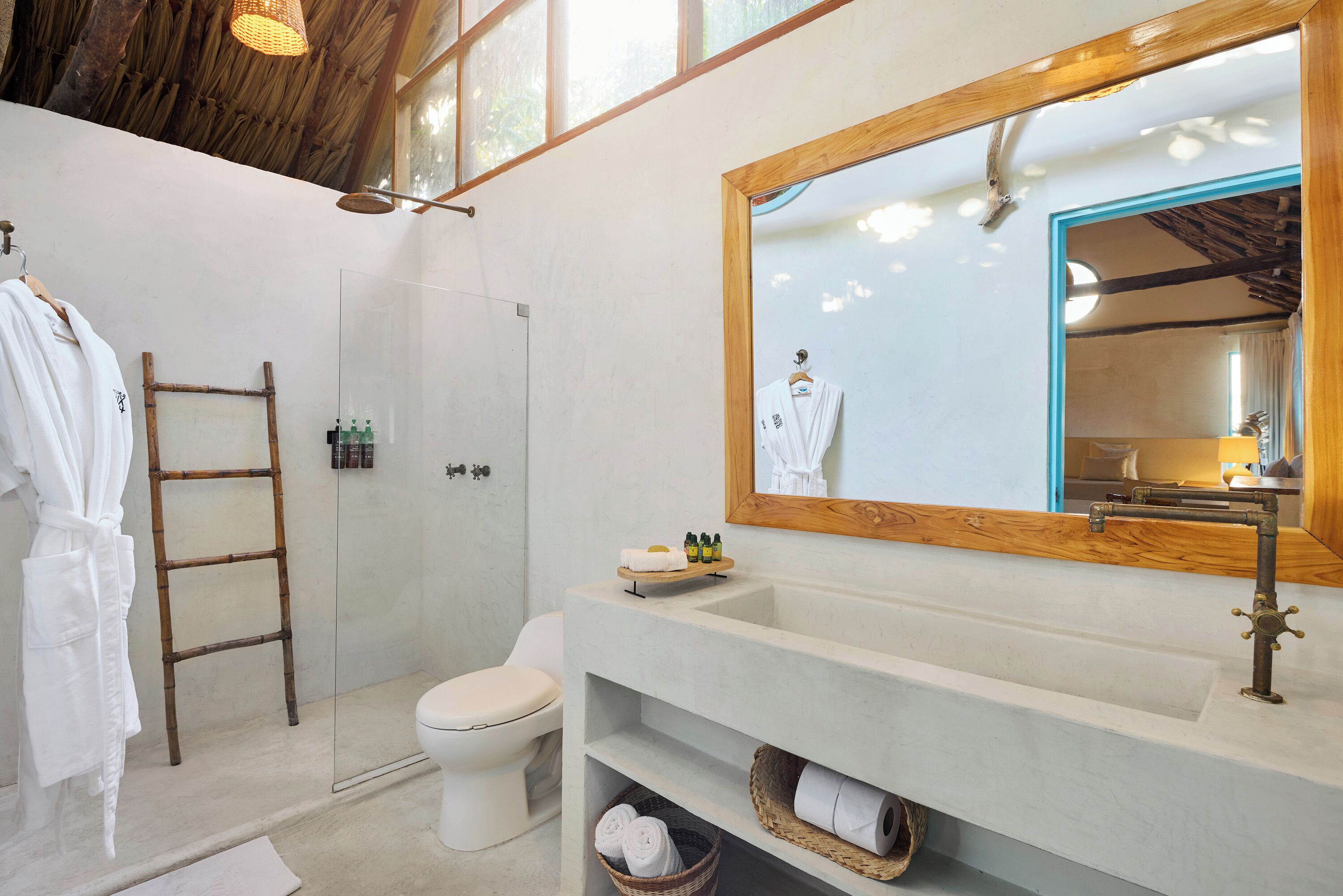 Un baño con escalera de madera, inodoro, lavabo con espejo y zona de ducha.