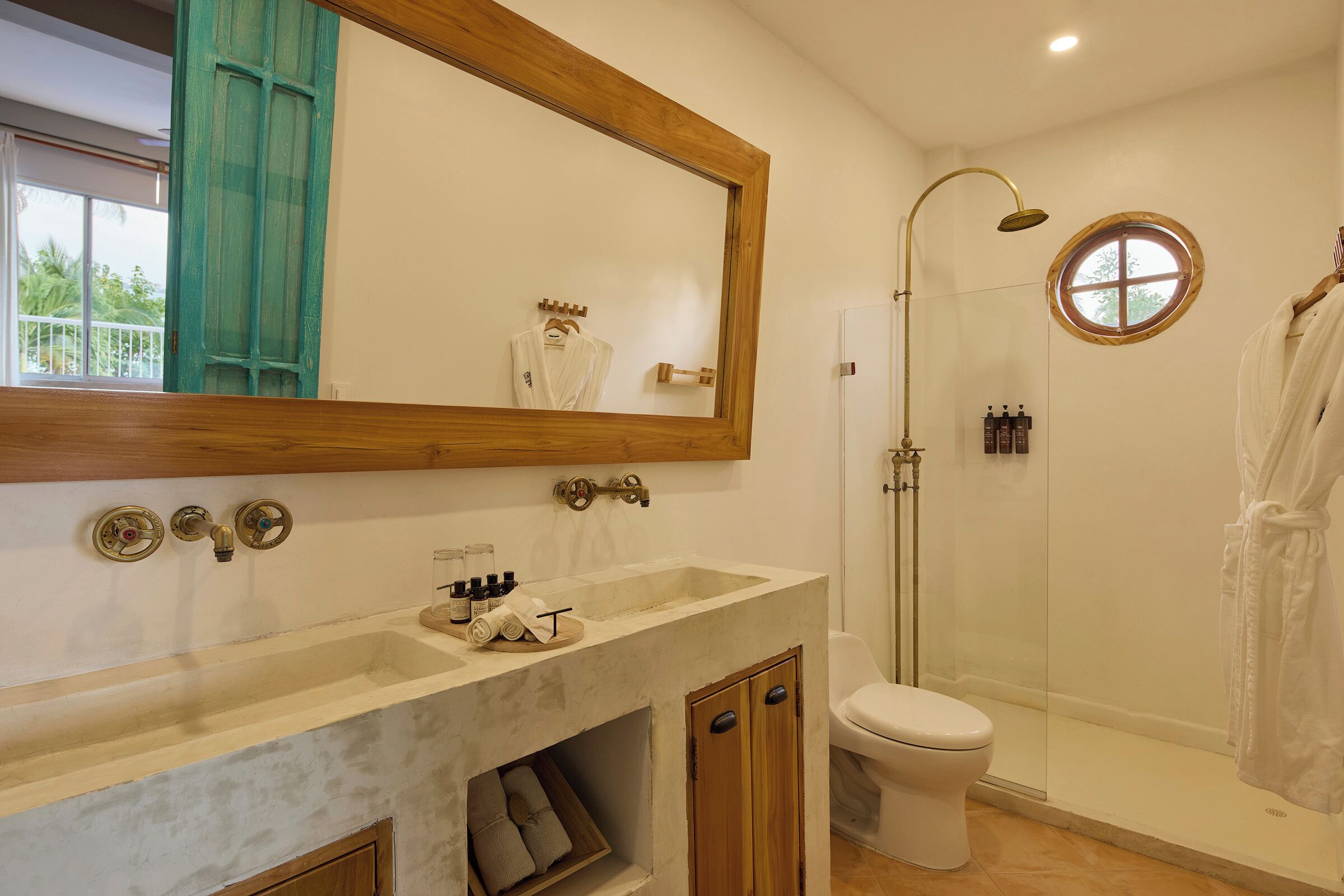 A bathroom with a marble sink, a large mirror, a toilet, and a glass-enclosed shower.