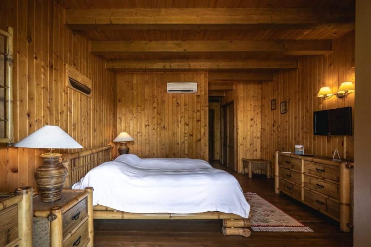 Ein Zimmer mit Holzboden, einem Bett, Nachttischlampen, einem Schminktisch und einem Fernseher.